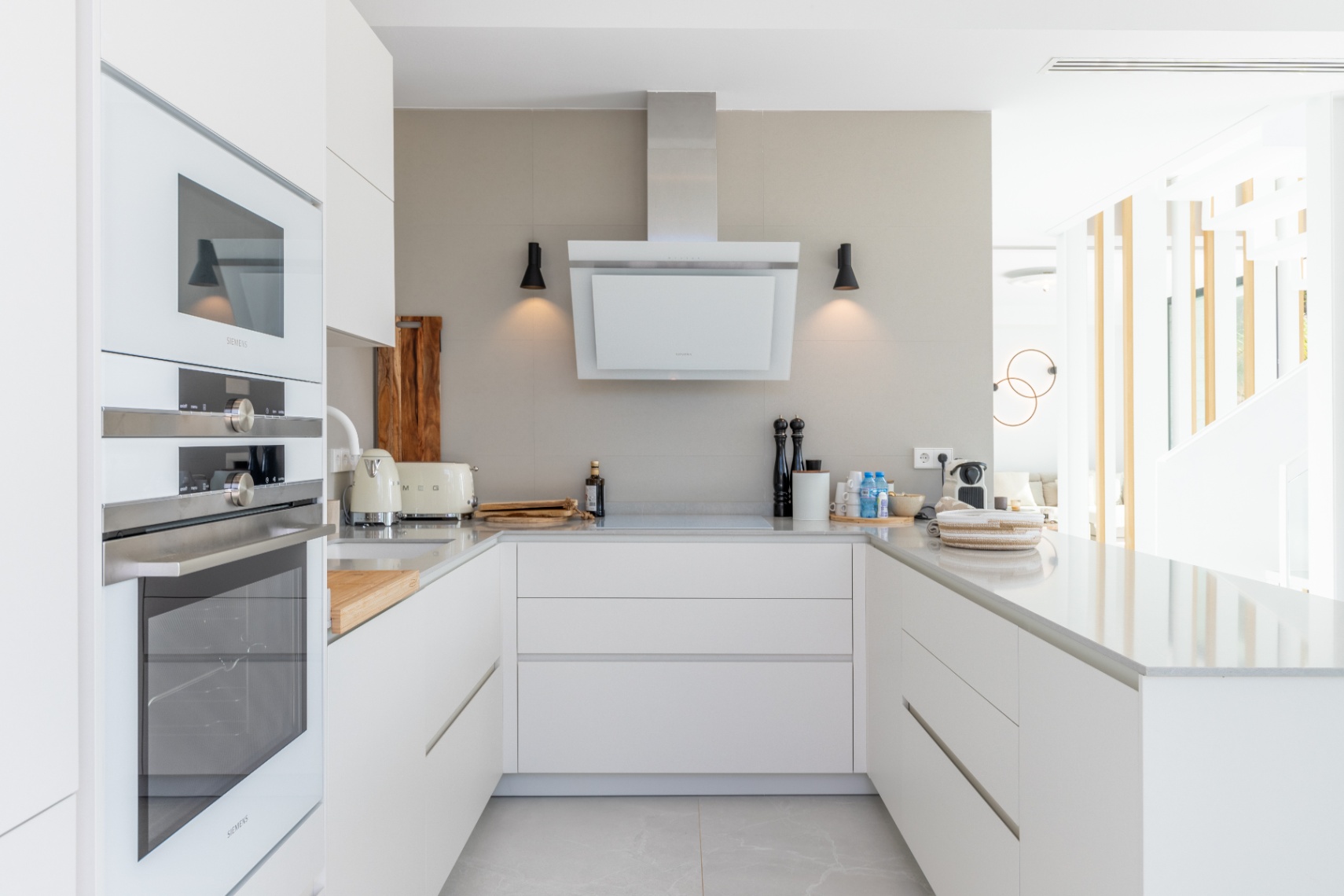 Moderne keuken met Siemens apparatuur, licht stenen werkbladen en een minimalistische afzuigkap.