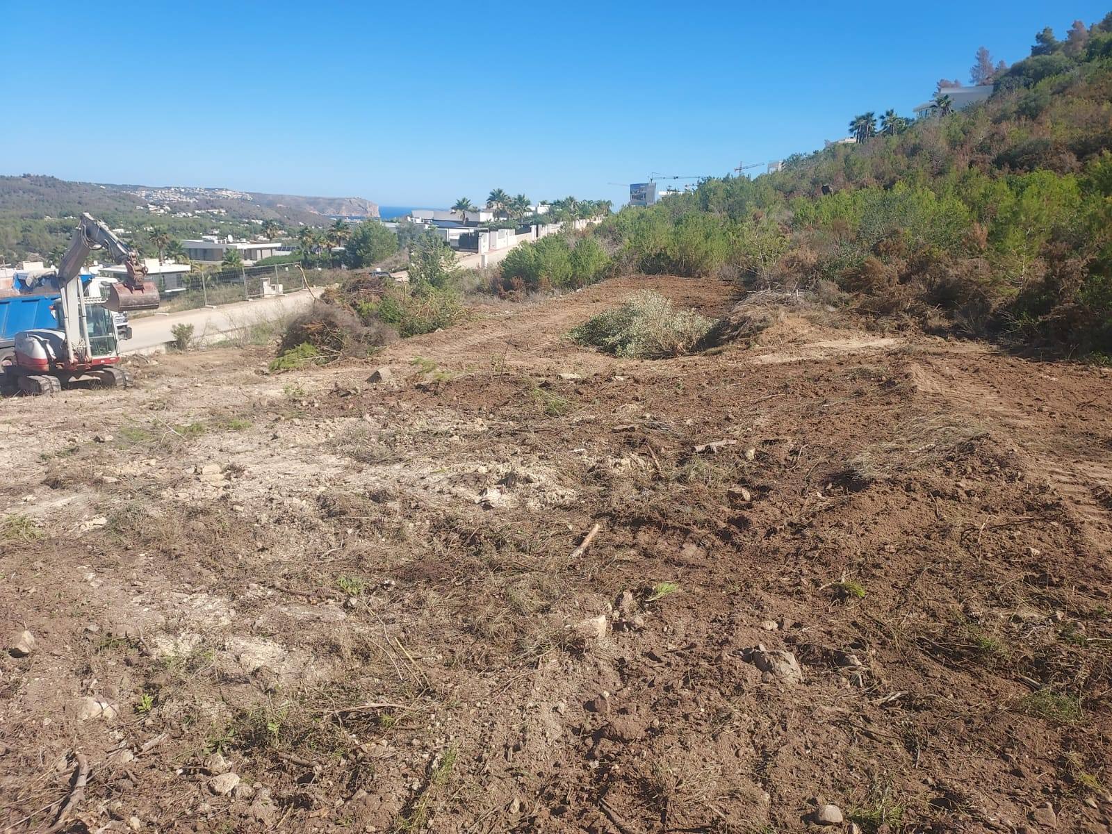 Terrein in voorbereiding in Jávea met graafmachine en uitzicht op zee.