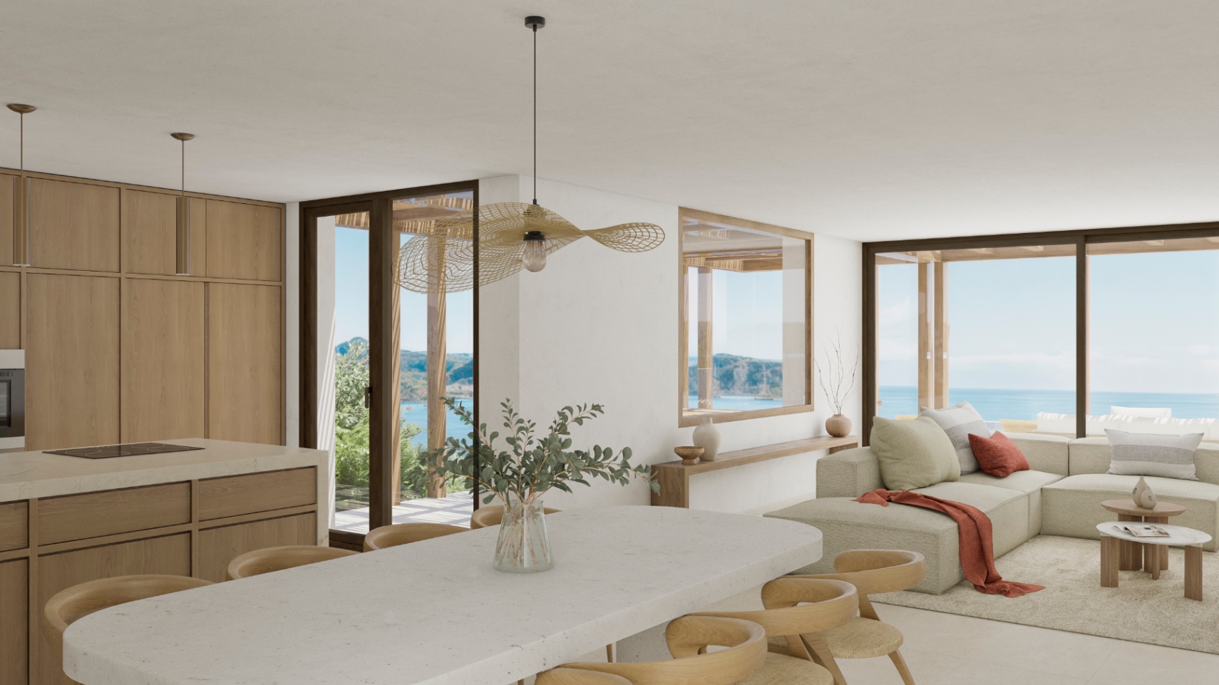 Licht interieur met open keuken, stenen eiland en uitzicht op zee.