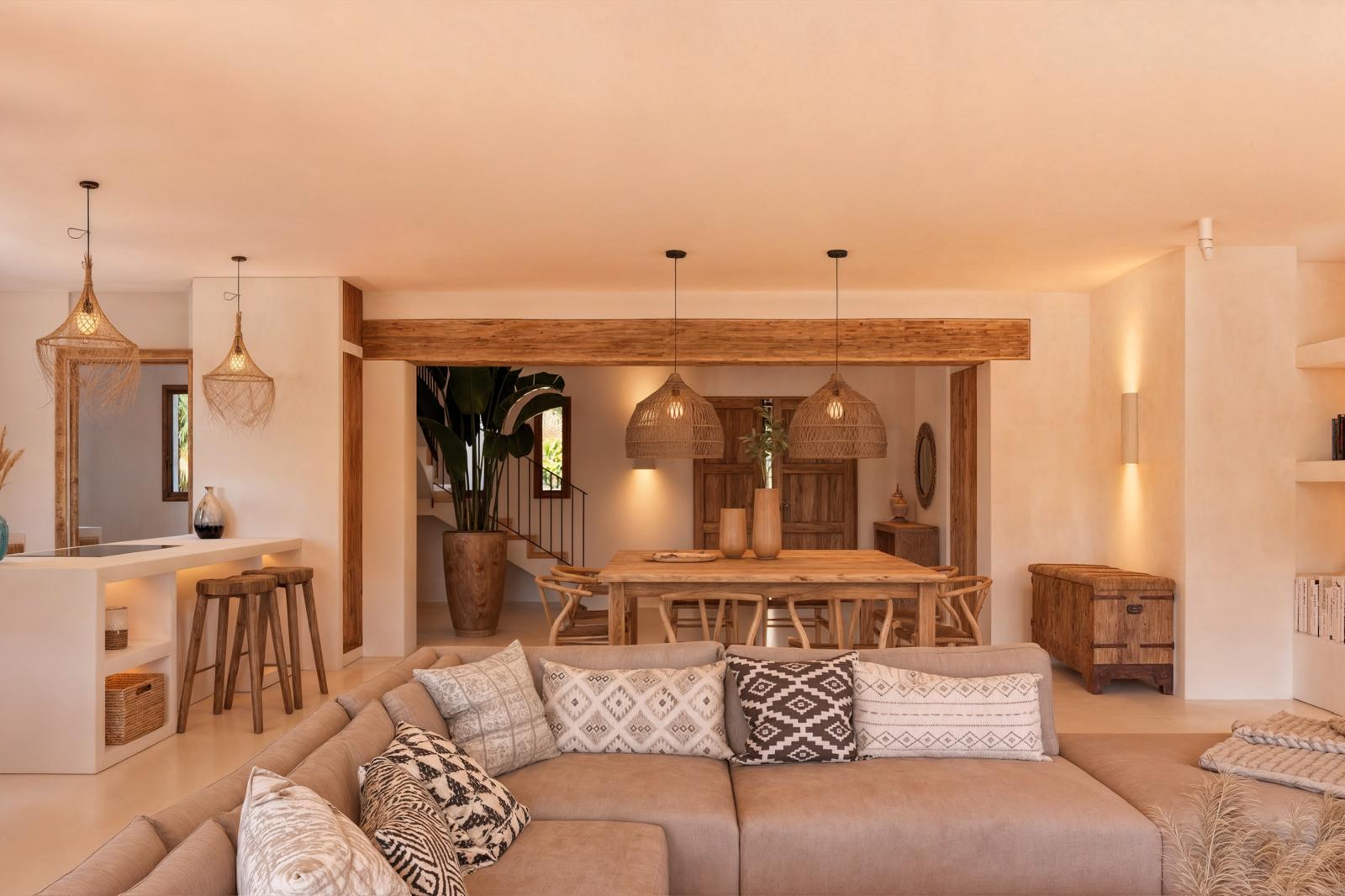 Open woon- en eetkamer met natuurlijke houten balken, geweven hanglampen en rustiek meubilair in warme mediterrane tinten.