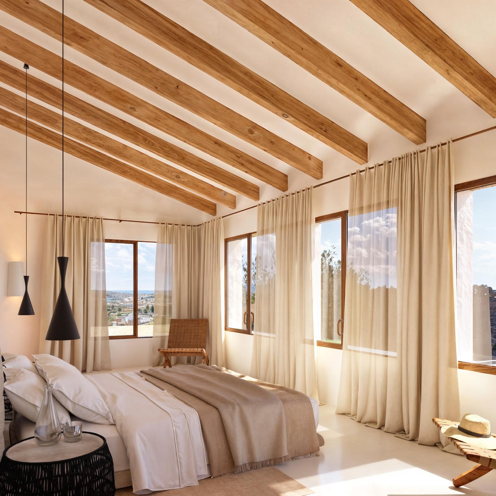 Slaapkamer met zichtbare houten plafondbalken, grote houten ramen en veel natuurlijk licht met panoramisch uitzicht op de kust.