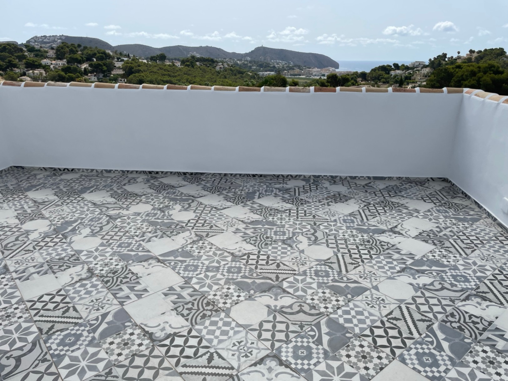 Zonnig dakterras met decoratieve patroontegels en panoramisch uitzicht over de Middellandse Zee en de kustlijn van Moraira.