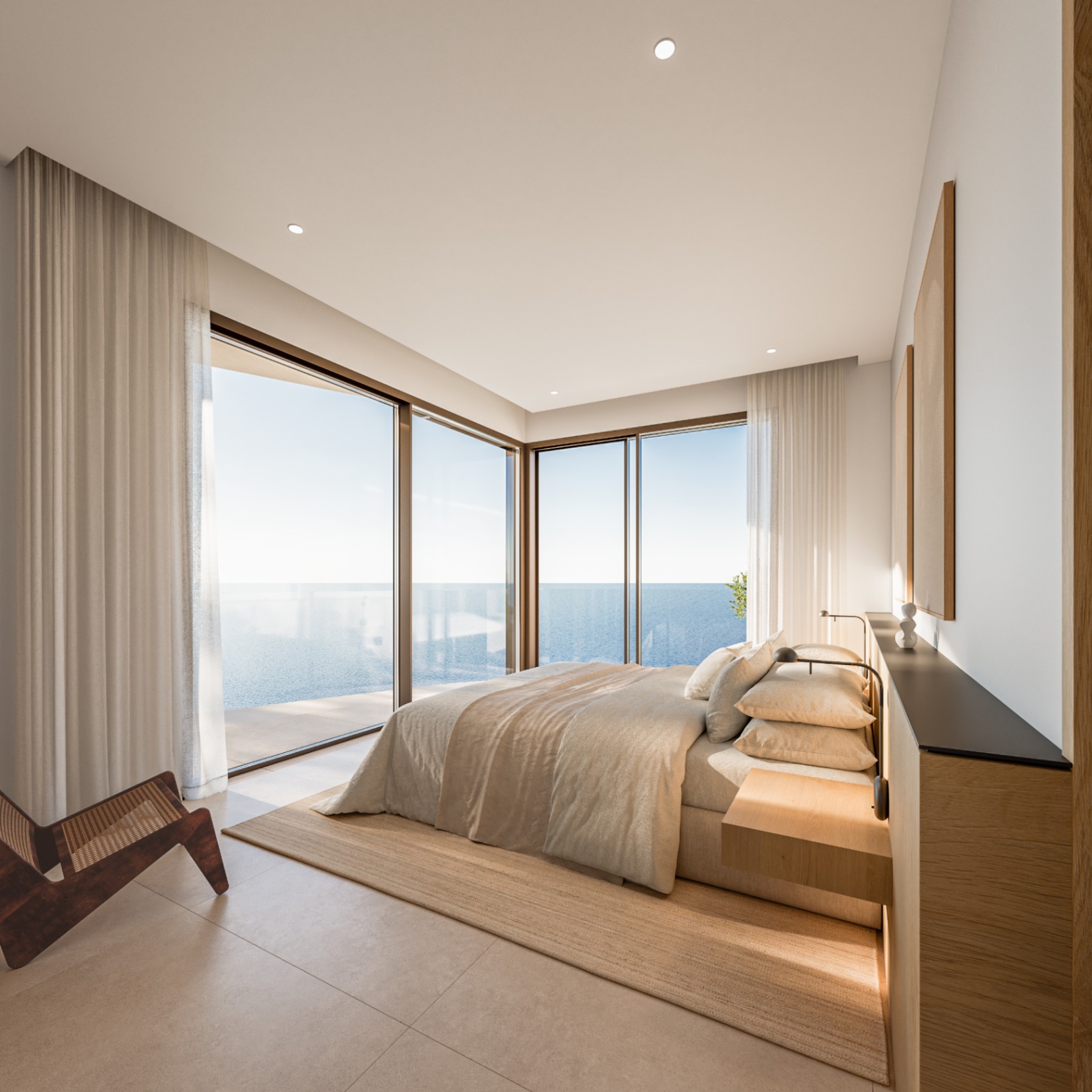 Hoofdslaapkamer met kamerhoge hoekramen en direct uitzicht op zee. Voorzien van minimalistisch houten meubilair, een designstoel en een rustgevend kleurenpalet.
