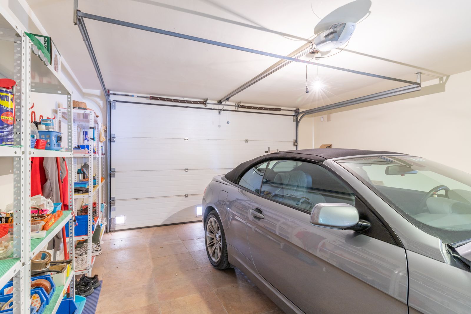 Garage met metalen rekken en een grijze cabriolet.