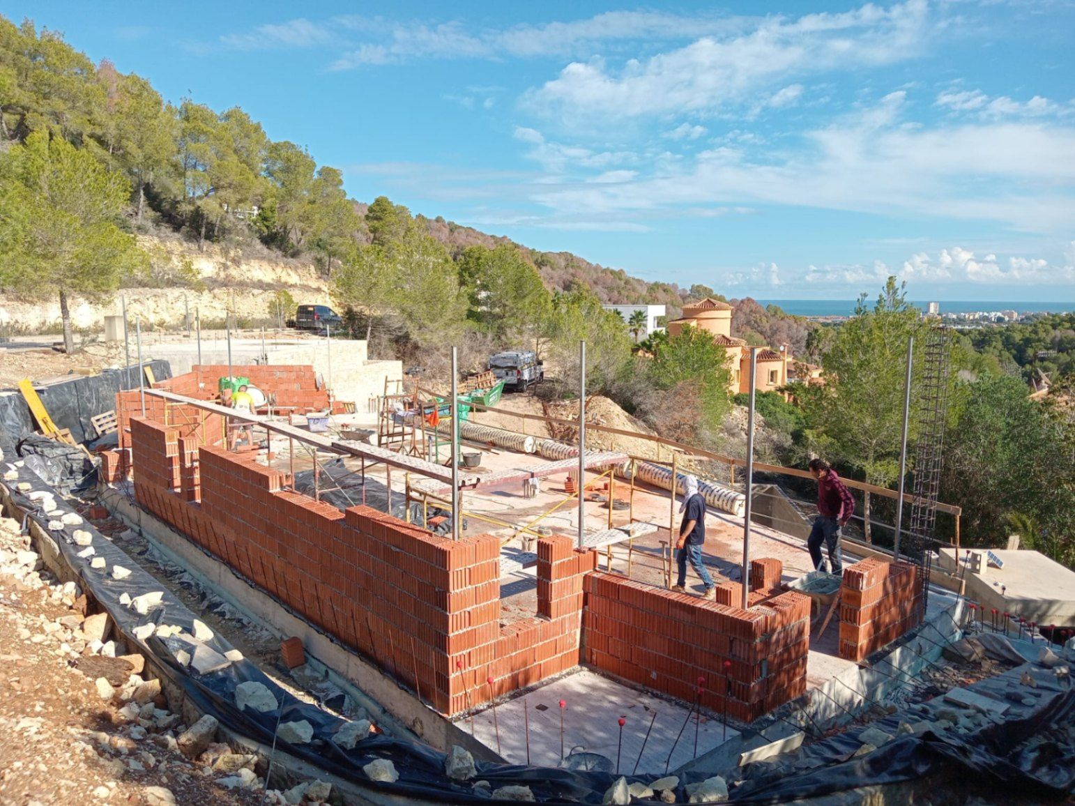 Eerste bouwfase van de villa in Jávea, met het optrekken van de muren op de fundering en een panoramisch uitzicht over de Middellandse Zee.