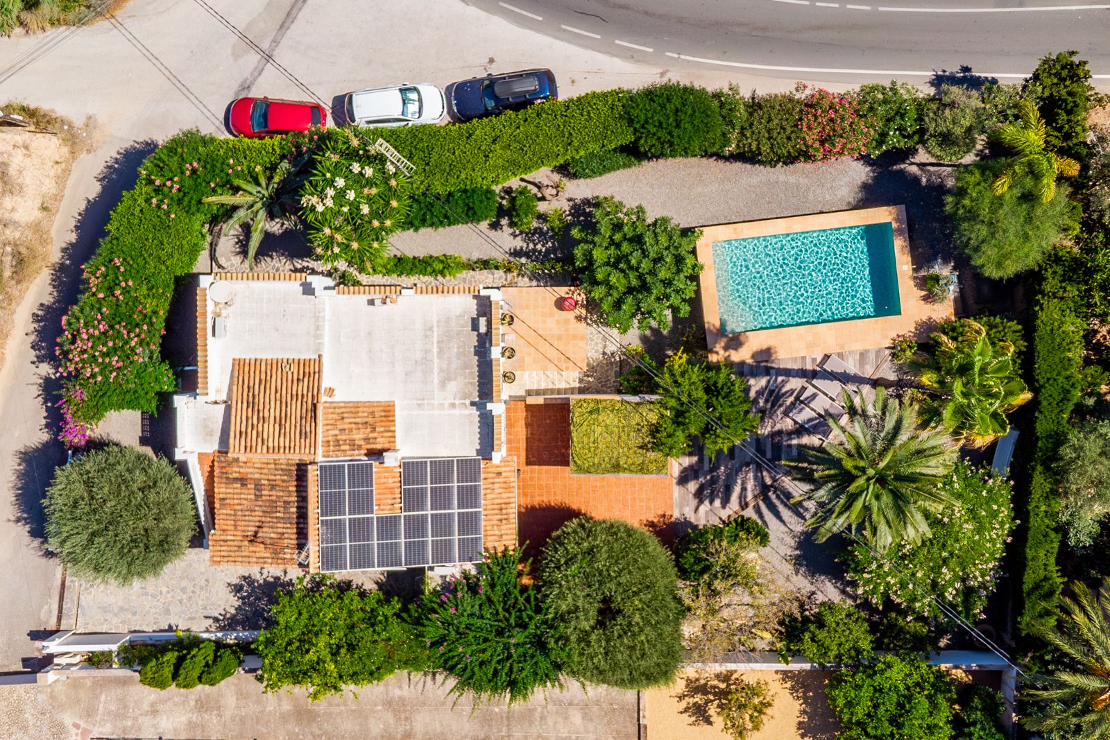 Bovenaanzicht van het perceel van 918 m² met het privézwembad, de zonnepanelen op het dak en de volgroeide mediterrane tuin.