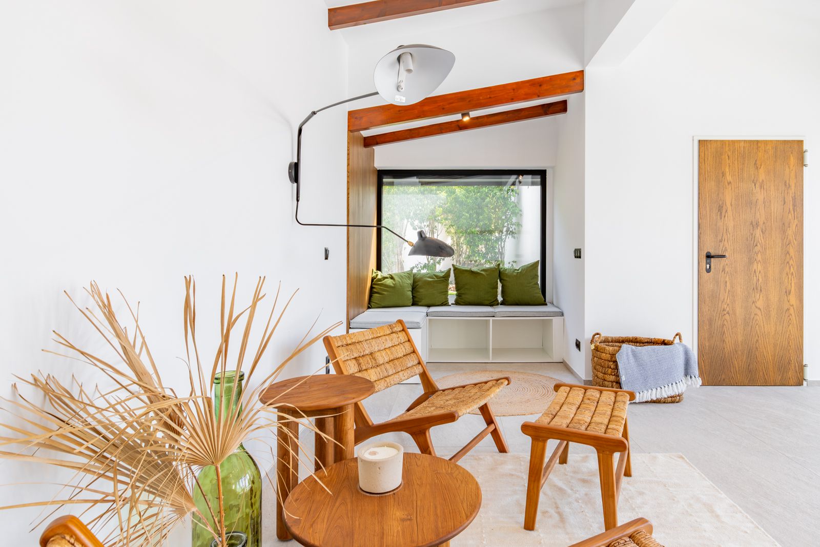 Leeshoek met ingebouwde vensterbank, houten balken en meubels van natuurlijke vezels. Voorzien van een design wandlamp en een massief eikenhouten binnendeur.