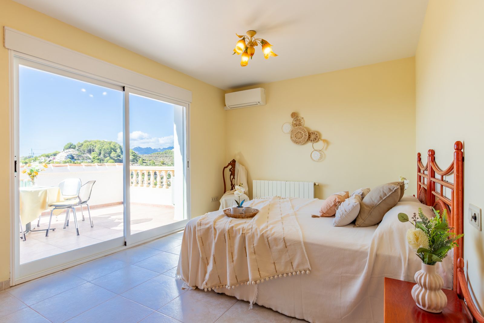 Lichte slaapkamer met directe toegang tot een privéterras. Voorzien van airconditioning, centrale verwarming en vrij uitzicht op de bergen van Moraira.