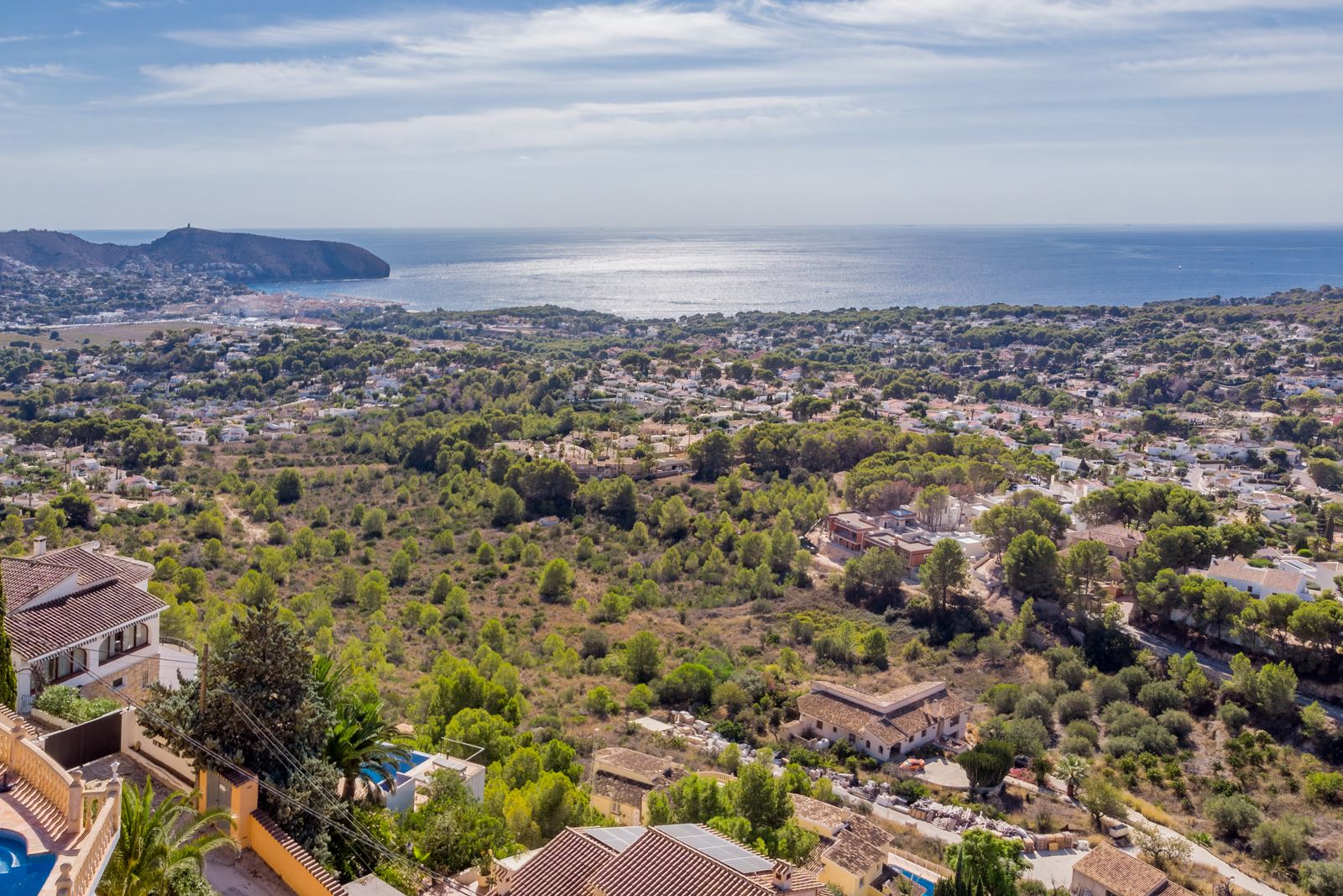 Panoramisch uitzicht op de Middellandse Zee en Cap d'Or vanuit Benimeit, met het groene kustlandschap en de kustlijn van Moraira onder een heldere hemel.