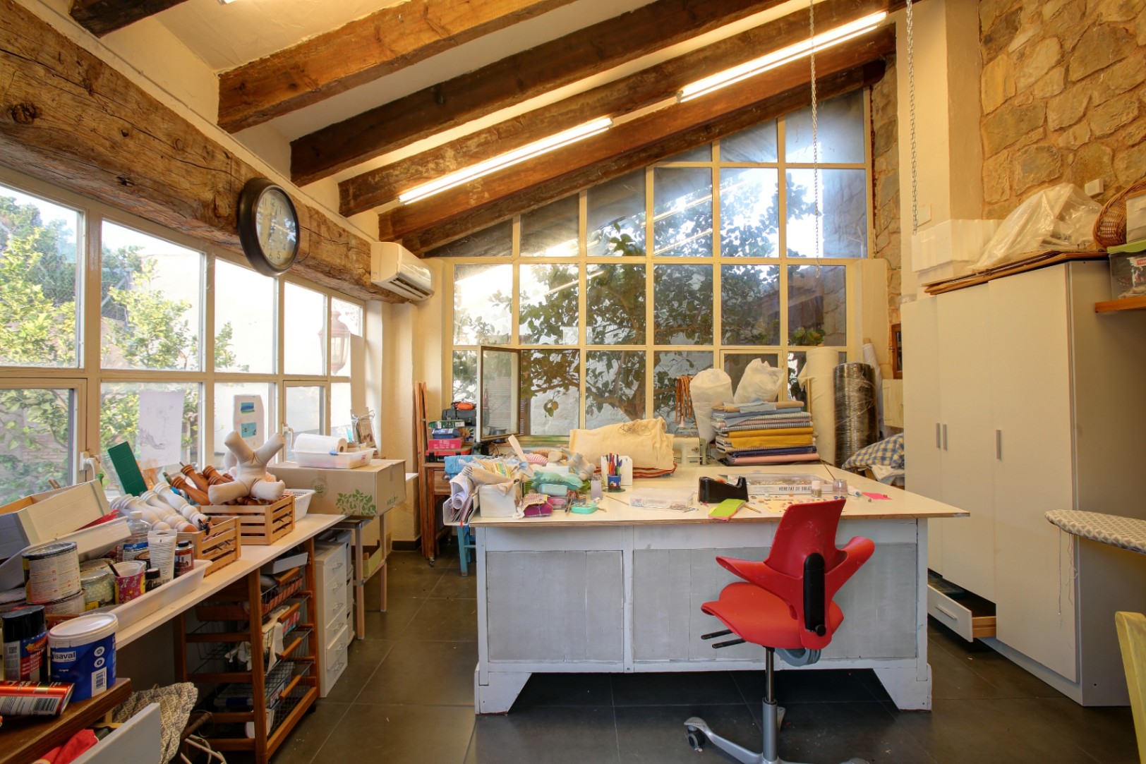 Creatief atelier met robuuste houten balken, natuurstenen muren en grote raampartijen die zorgen voor een lichte en inspirerende werkruimte.