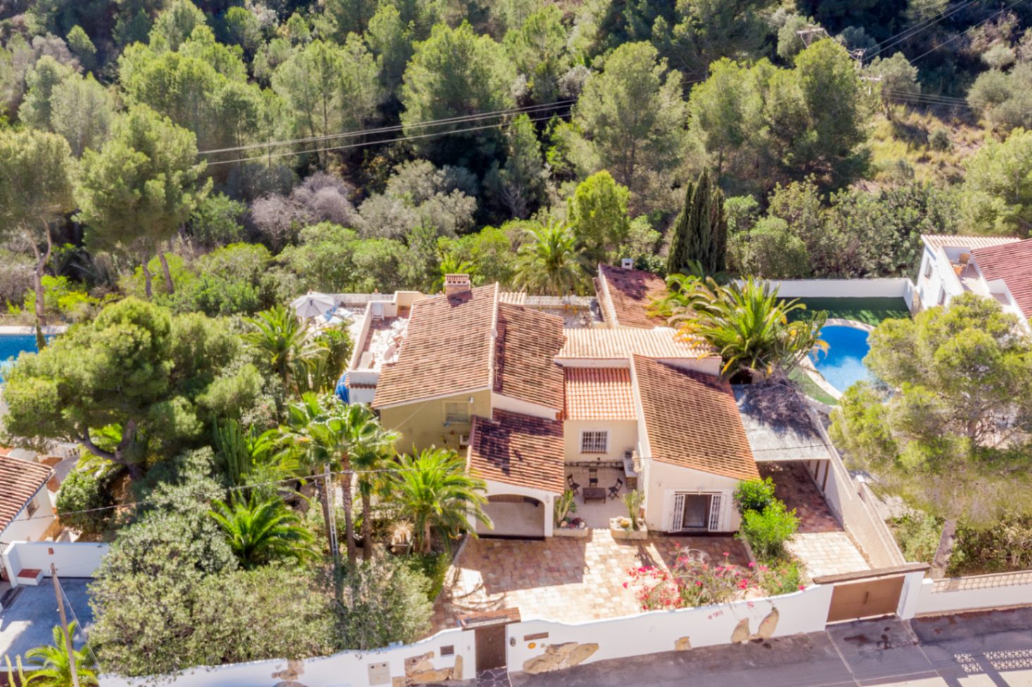 Luchtfoto van de villa met mediterrane architectuur en pannendaken, omgeven door een beschermd natuurgebied en volwassen palmbomen voor volledige privacy.