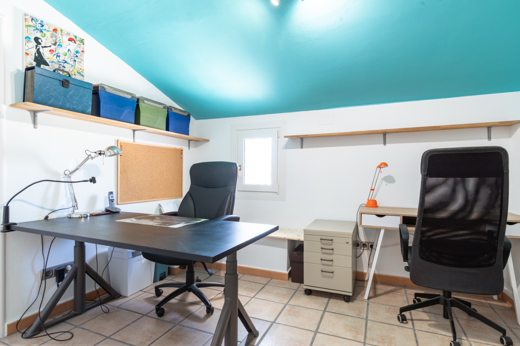 Functioneel thuiskantoor met een opvallend turquoise schuin plafond, twee werkplekken, een tegelvloer en houten wandplanken.