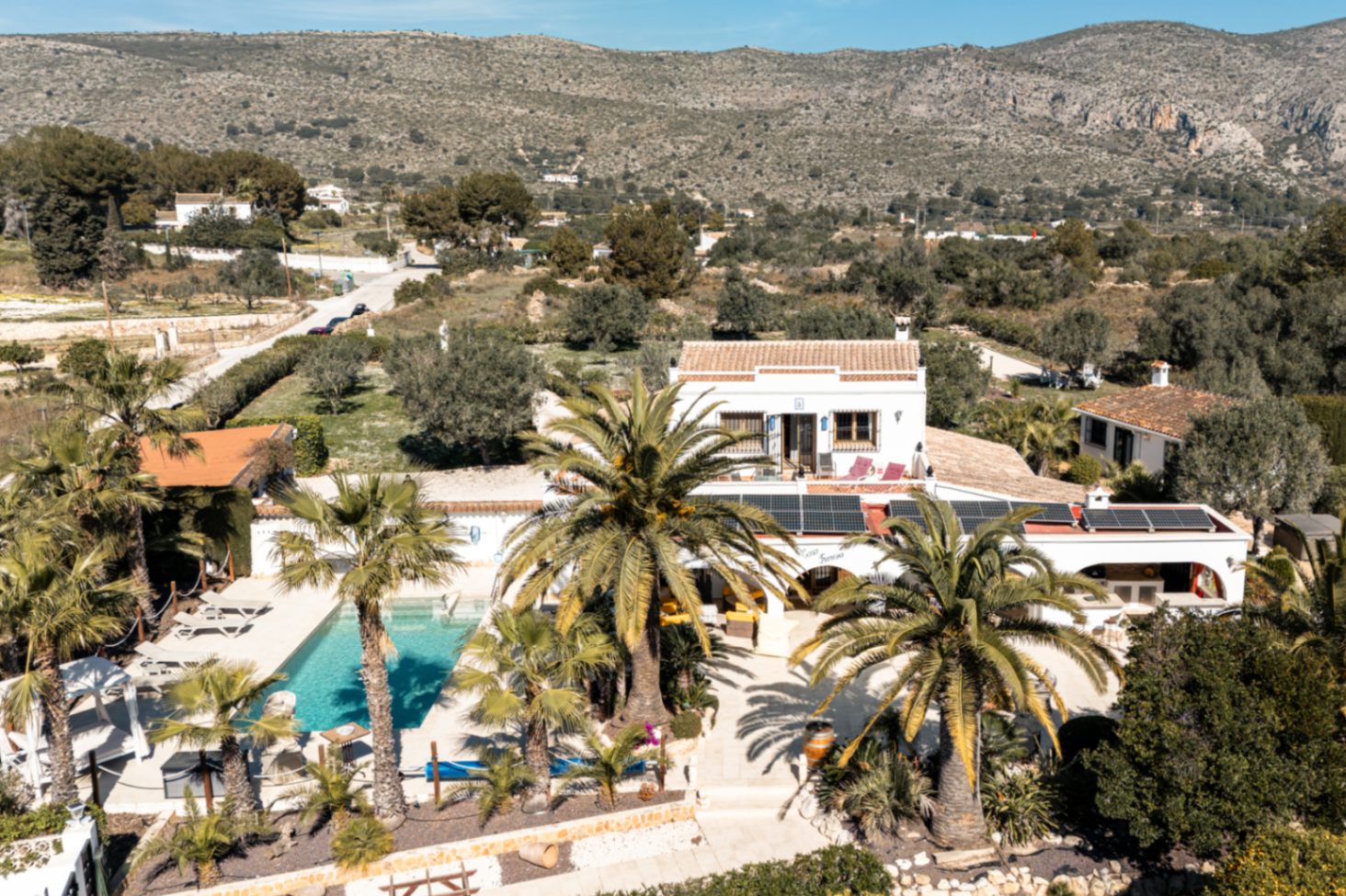 Luchtfoto van het landgoed met het privézwembad, zonnepanelen op het dak en de mediterrane tuin met uitzicht op de bergen.