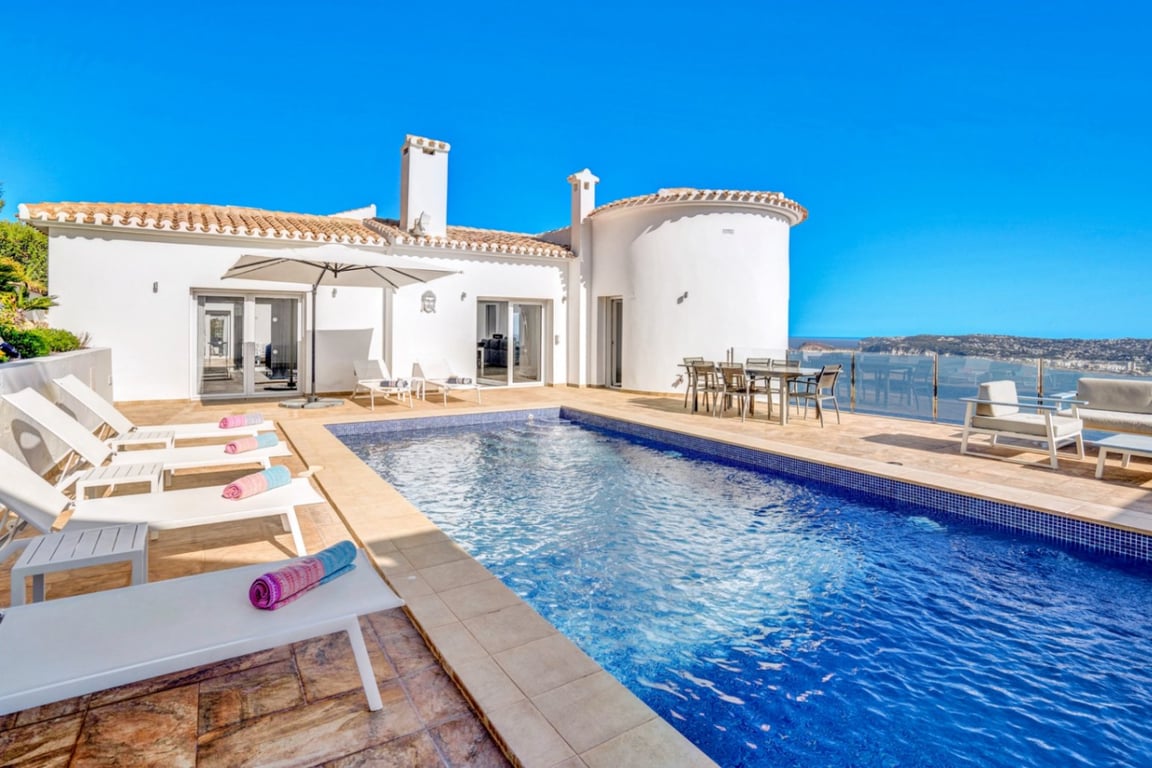 Hoofdterras met buitenzwembad, ligbedden en eethoek buiten met panoramisch uitzicht over de zee en de haven van Jávea.