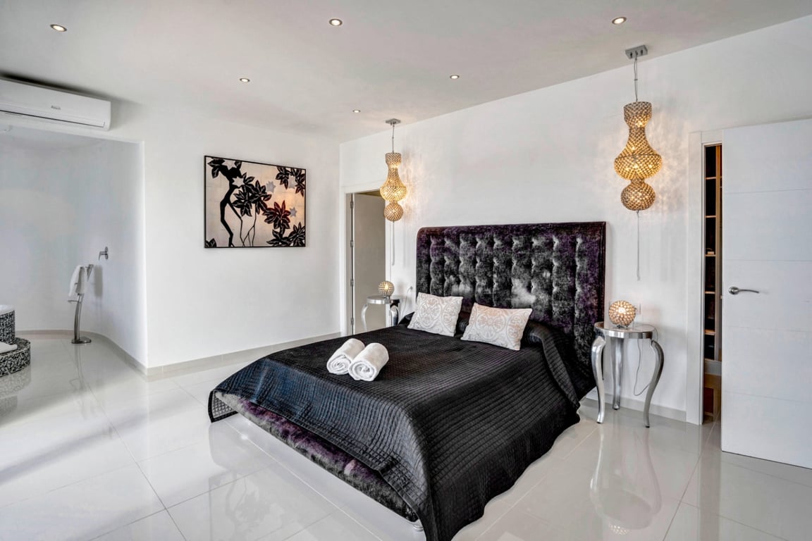 Slaapkamer met gecapitonneerd fluwelen hoofdbord, gepolijste porseleinen tegelvloer, decoratieve hanglampen en individuele airconditioning.