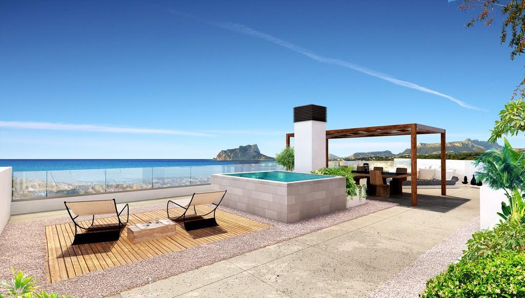 Dakterras met verhoogd zwembad, eethoek onder een houten pergola en panoramisch uitzicht op de Middellandse Zee en de Peñón de Ifach.