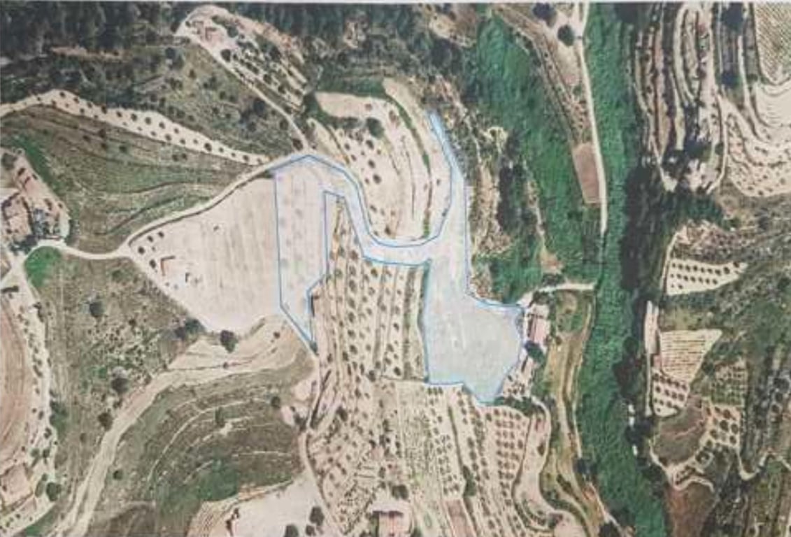 Luchtfoto met de omtrek van het perceel, waarop de terrasvormige topografie en de verspreide beplanting in de natuurlijke omgeving zichtbaar zijn.
