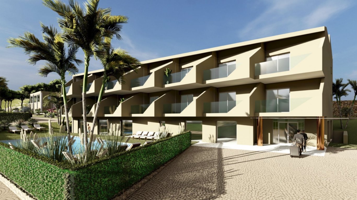 Exterieur van het drie verdiepingen tellende boetiekhotel met privébalkons met glazen balustrades, een zwembad met ligstoelen en een geplaveide entree.