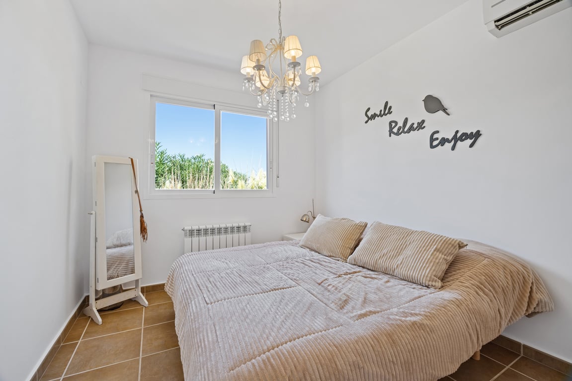 Lichte slaapkamer voorzien van een tegelvloer, split-airconditioning, centrale verwarming en een raam met dubbel glas met uitzicht op de tuin.