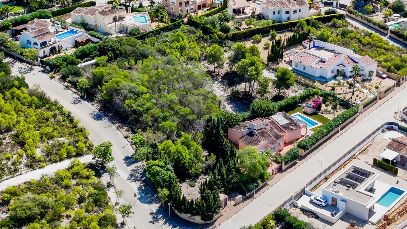Luchtfoto van de villa met gelijkvloerse indeling, privézwembad en zonnepanelen op het dak, gelegen op een volledig omheind vlak perceel.