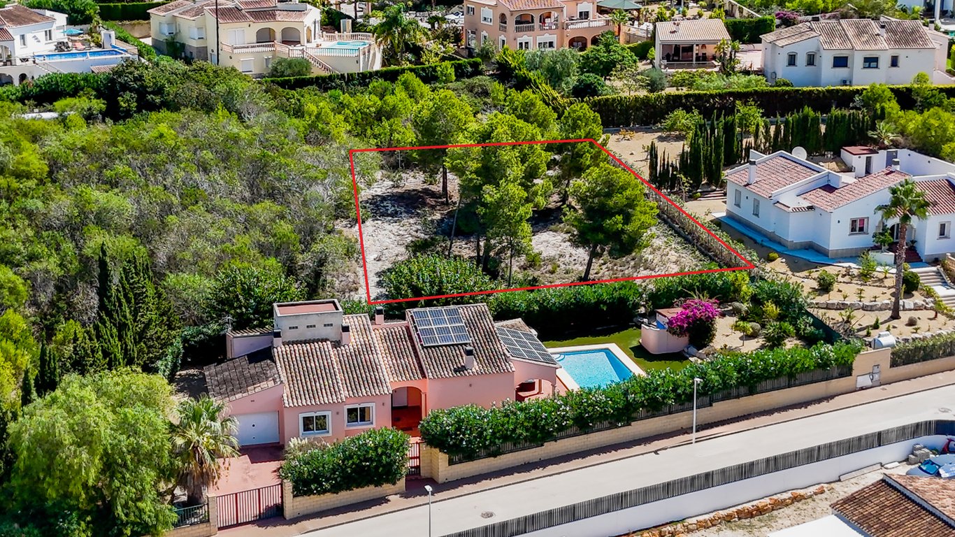 Luchtfoto van de villa met zonnepanelen en zwembad, inclusief het aangrenzende bouwperceel dat rood is omkaderd.