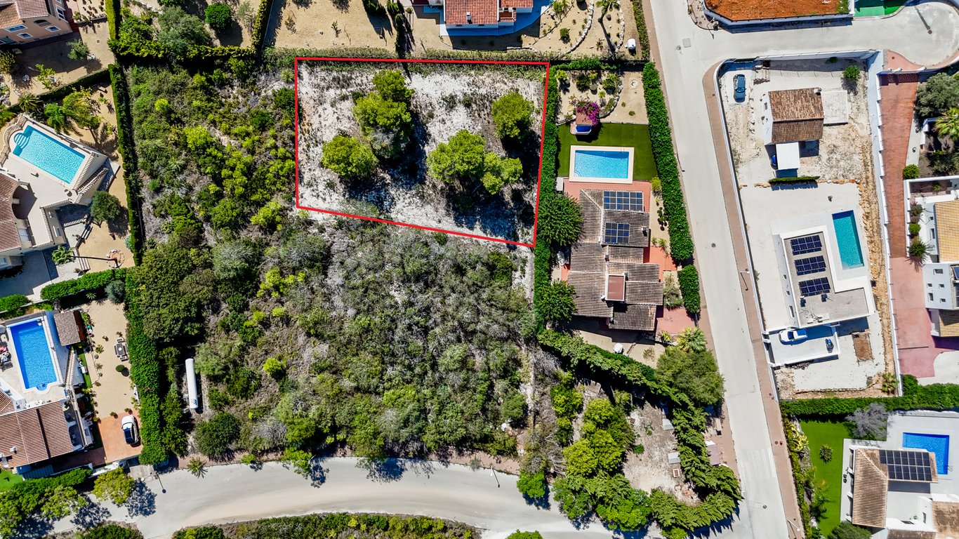 Luchtfoto van de villa met zonnepanelen en zwembad, met weergave van het aangrenzende bouwperceel dat rood is omkaderd.