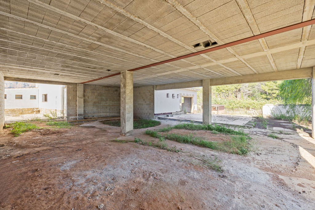 Ruime open casco ruimte met betonnen kolommen en balkenplafonds, die een solide structurele basis biedt voor een gepersonaliseerde indeling en natuurlijk licht.