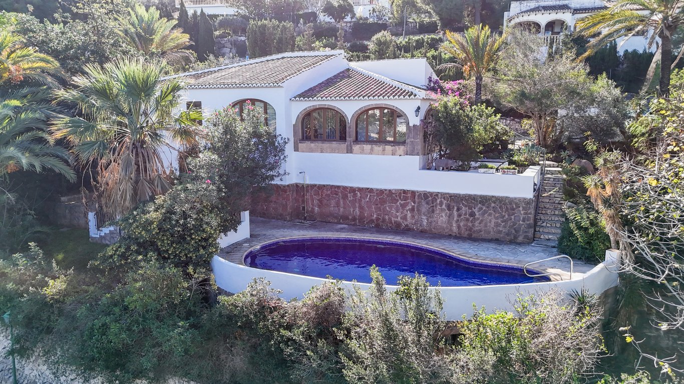 Exterieur van de villa met een ovaal privézwembad, natuurstenen muren en een traditionele naya met bogen van Tosca-steen.