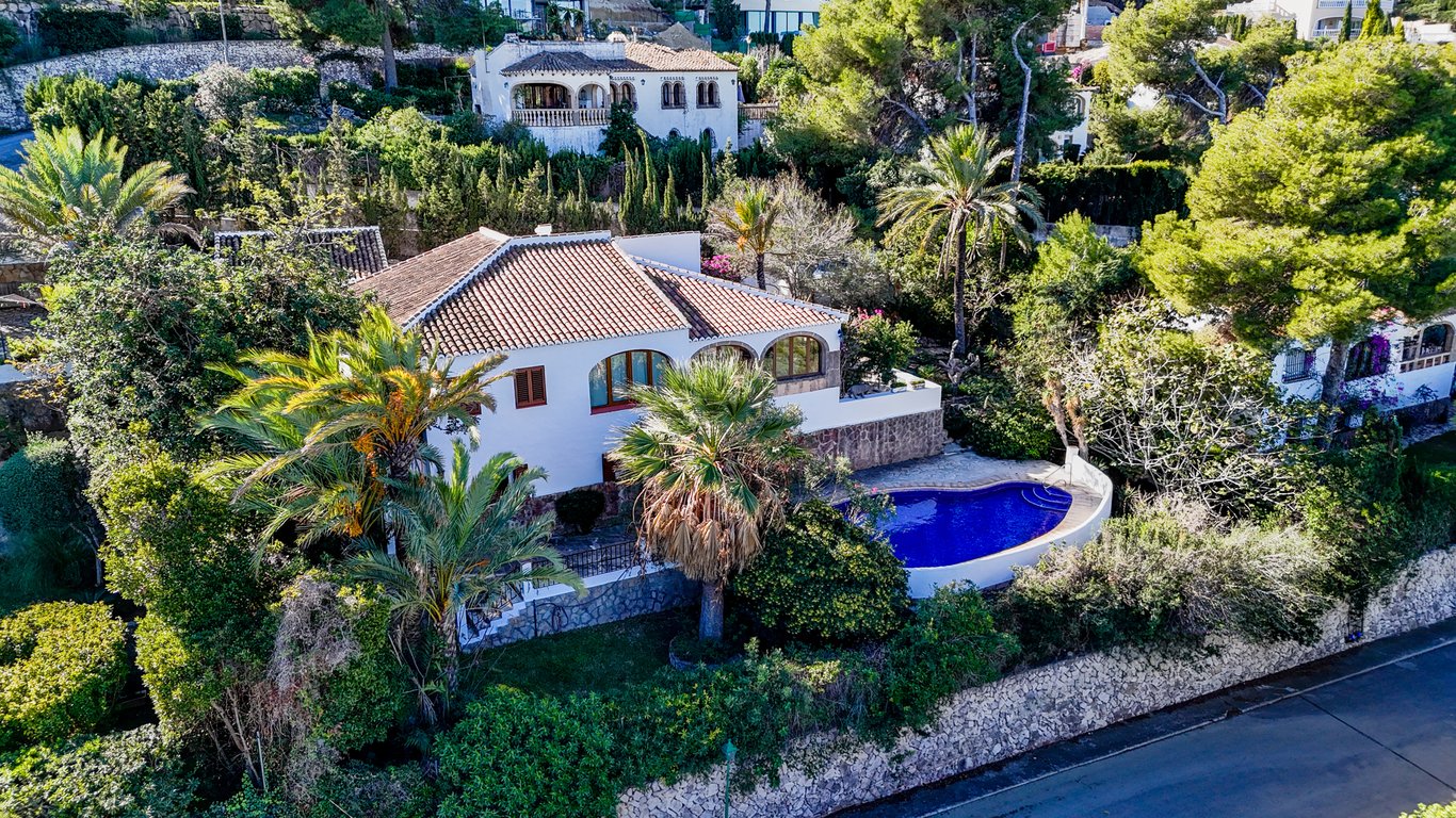 Luchtfoto van de traditionele villa met niervormig zwembad, naya met bogen en weelderige mediterrane tuin omgeven door natuurstenen muren.