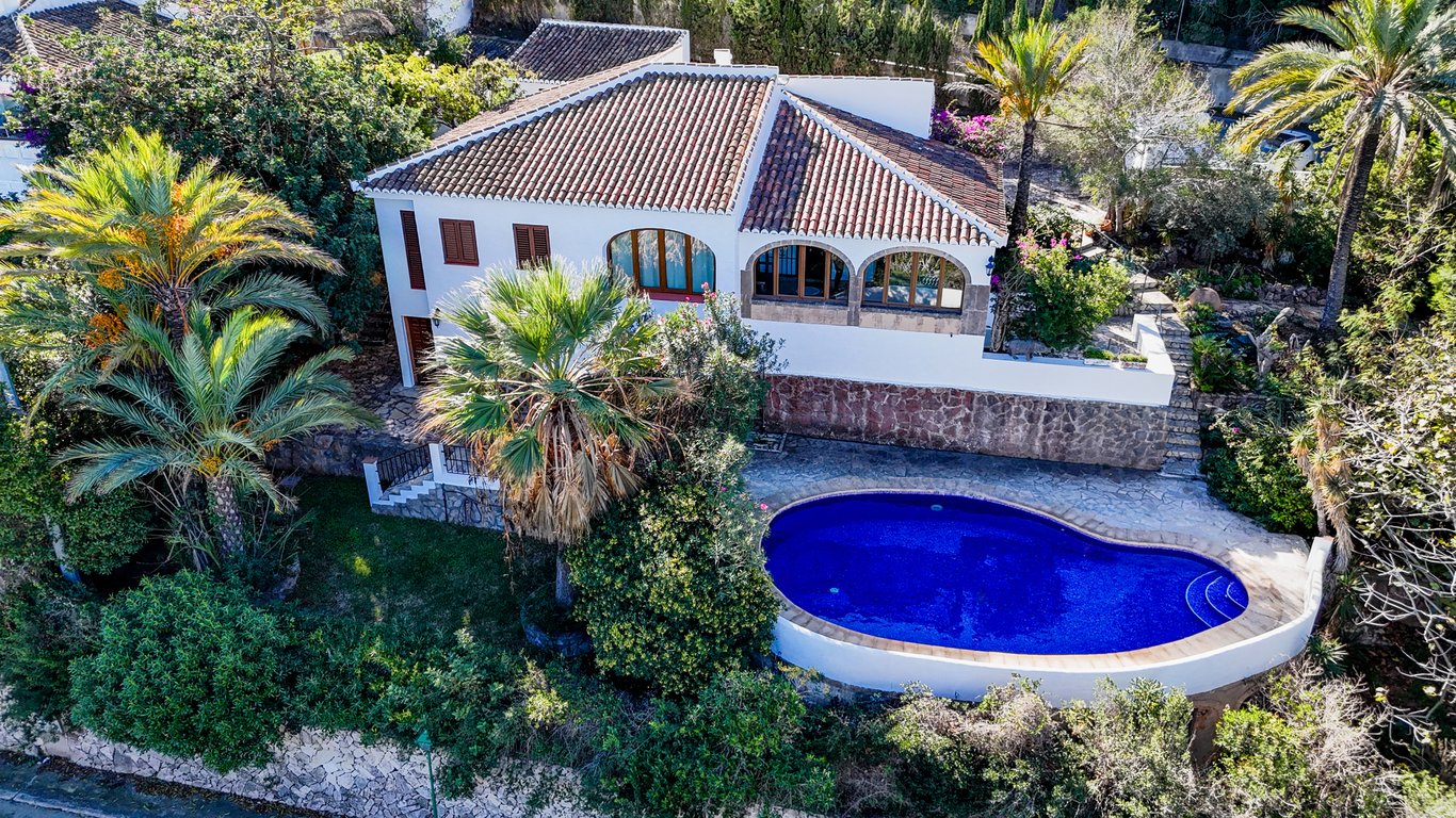 Luchtfoto van de villa met niervormig privézwembad, omgeven door mediterrane begroeiing, palmbomen en een naya met authentieke bogen van Tosca-natuursteen.