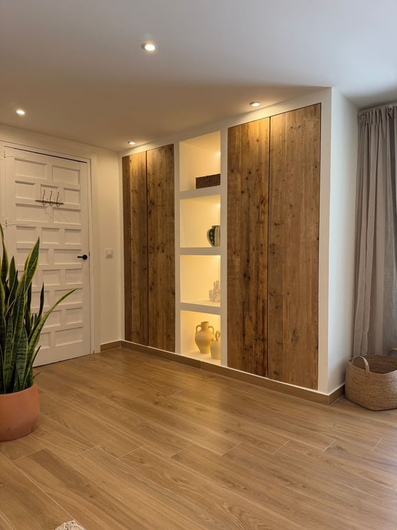 Inbouwkast met rustieke houten deuren en geïntegreerde nissen met LED-verlichting, gecombineerd met een keramische vloer met houtlook en inbouwspots.