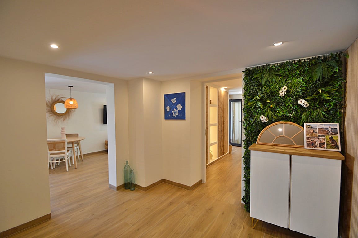 Lichte hal met houtlook vloer, inbouwspots en een decoratieve plantenwand naast een modern dressoir, grenzend aan de eetkamer.