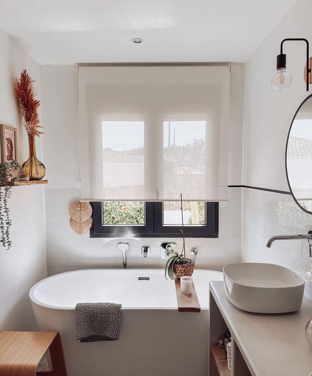 Moderne badkamer met vrijstaand bad, opzetwastafel en zwart raamkozijn. Witte metrotegels en houten details versterken de serene, mediterrane uitstraling.