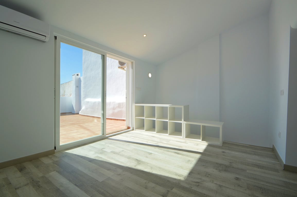 Lichte kamer met een lichte houtlook vloer, airconditioning en directe toegang tot het betegelde terras via een grote glazen schuifpui.