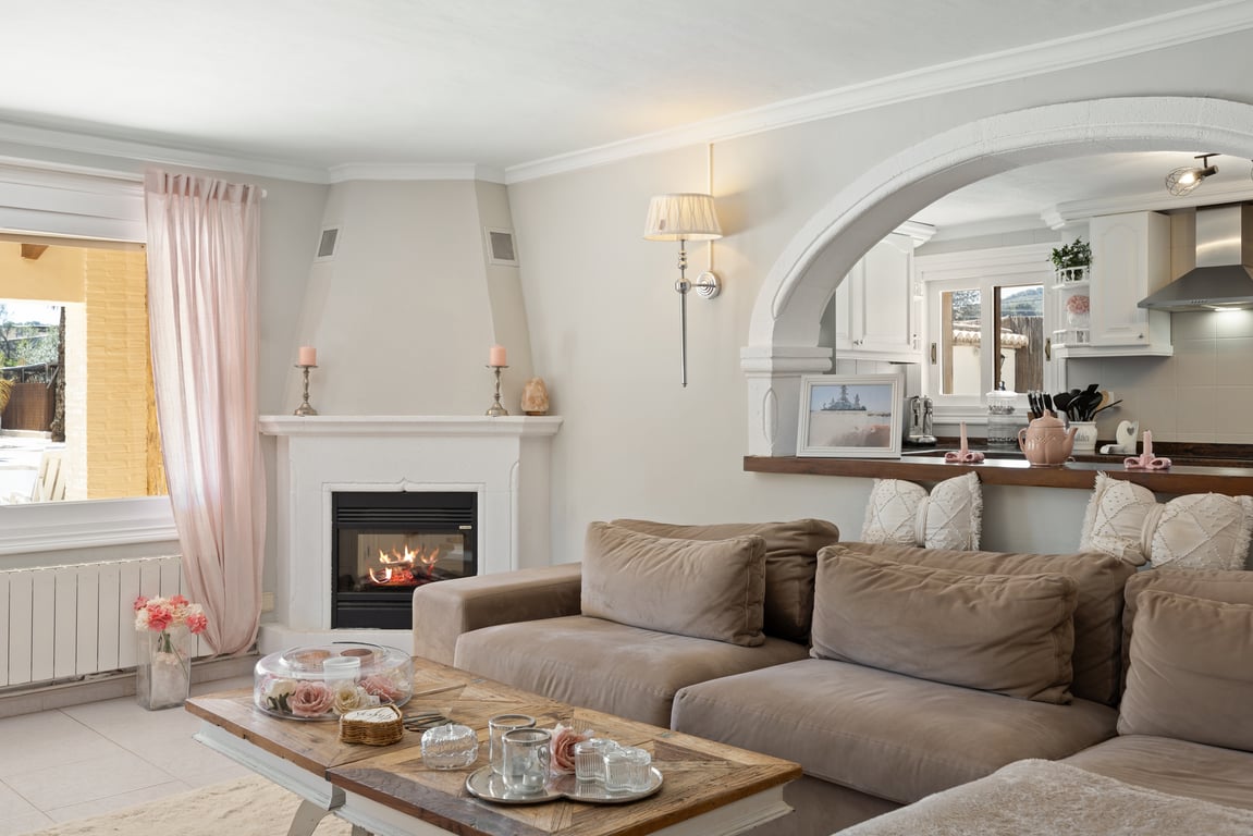 Lichte woonkamer met een hoekhaard, modulaire bank in neutrale tinten en een karakteristieke boog die uitkijkt op de keuken.