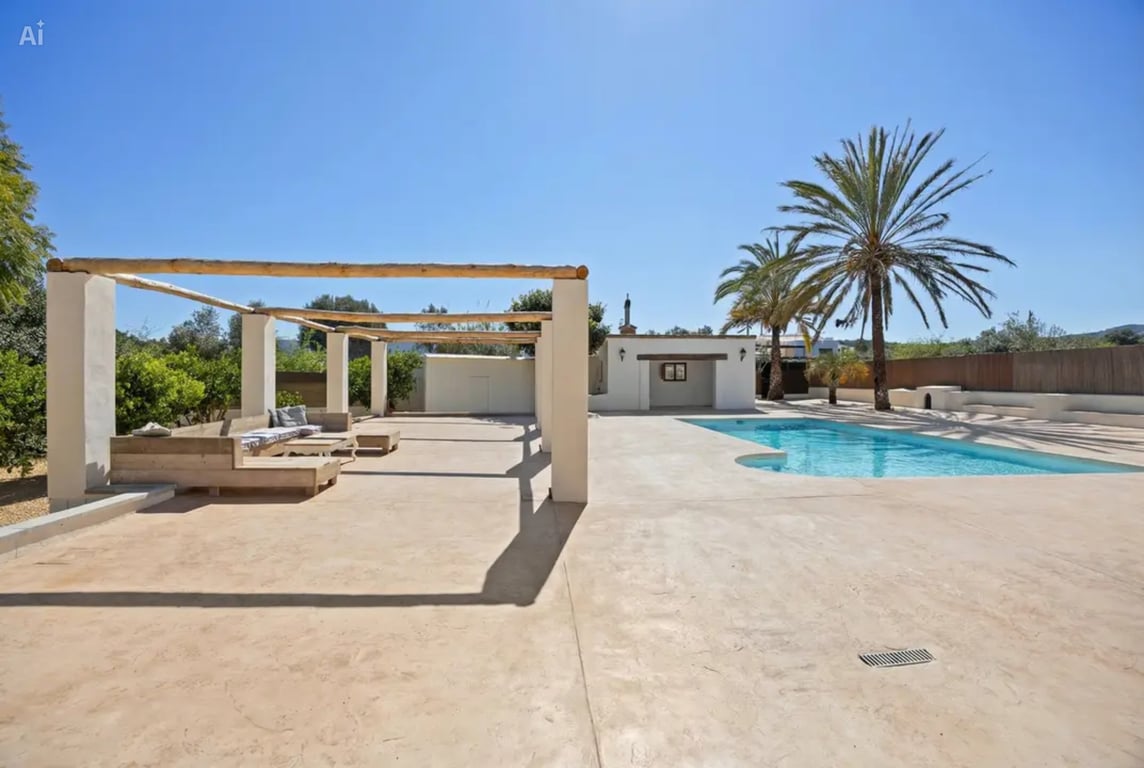 Zwembadgedeelte met een groot geplaveid terras, een rustieke houten pergola met ingebouwde zithoek en volgroeide palmbomen in een mediterrane tuin.