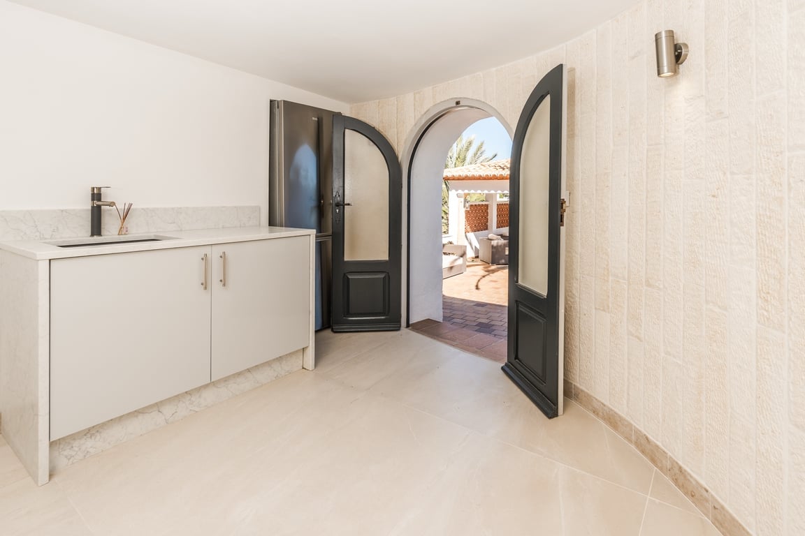 Compacte kitchenette met marmeren werkblad en natuurstenen wanden, verbonden met het buitenterras via een karakteristieke boogdeur.