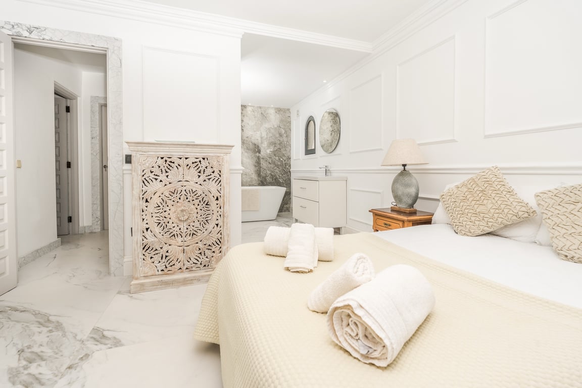Master suite met open badkamer, vrijstaand ligbad en natuurstenen wand. Voorzien van marmeren vloeren, klassieke wandlijsten en decoratief houtsnijwerk.