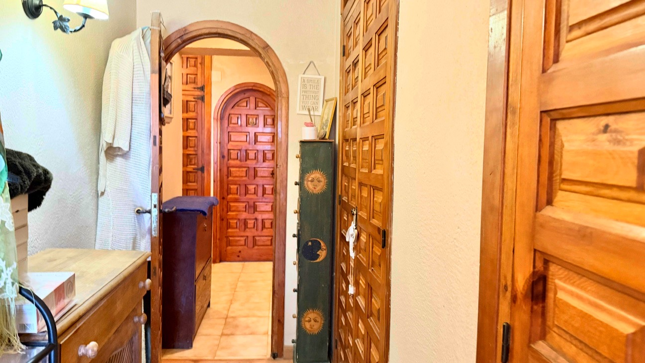 Hal met traditionele houten bogen en massief houten paneeldeuren, afgewerkt met een lichte tegelvloer en natuurlijke lichtinval.
