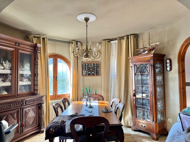 Traditionele eetkamer met massief houten vitrinekasten, een klassieke kroonluchter en een karakteristiek boogvenster met houten kozijnen.