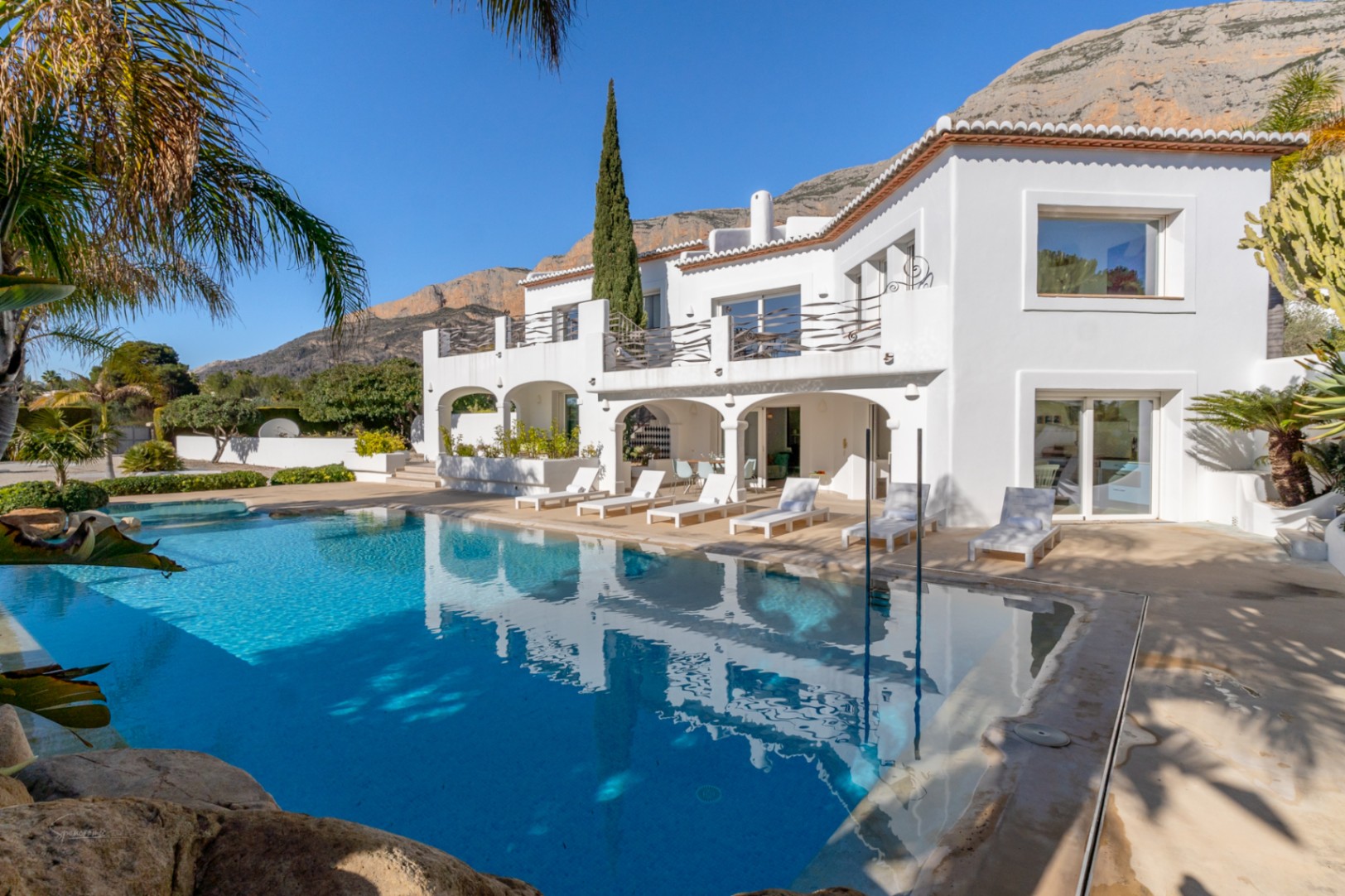 Exterieur van de villa in Ibiza-stijl met een zwembad van 70m², naya met bogen en een ruim terras met uitzicht op de Montgó-berg.