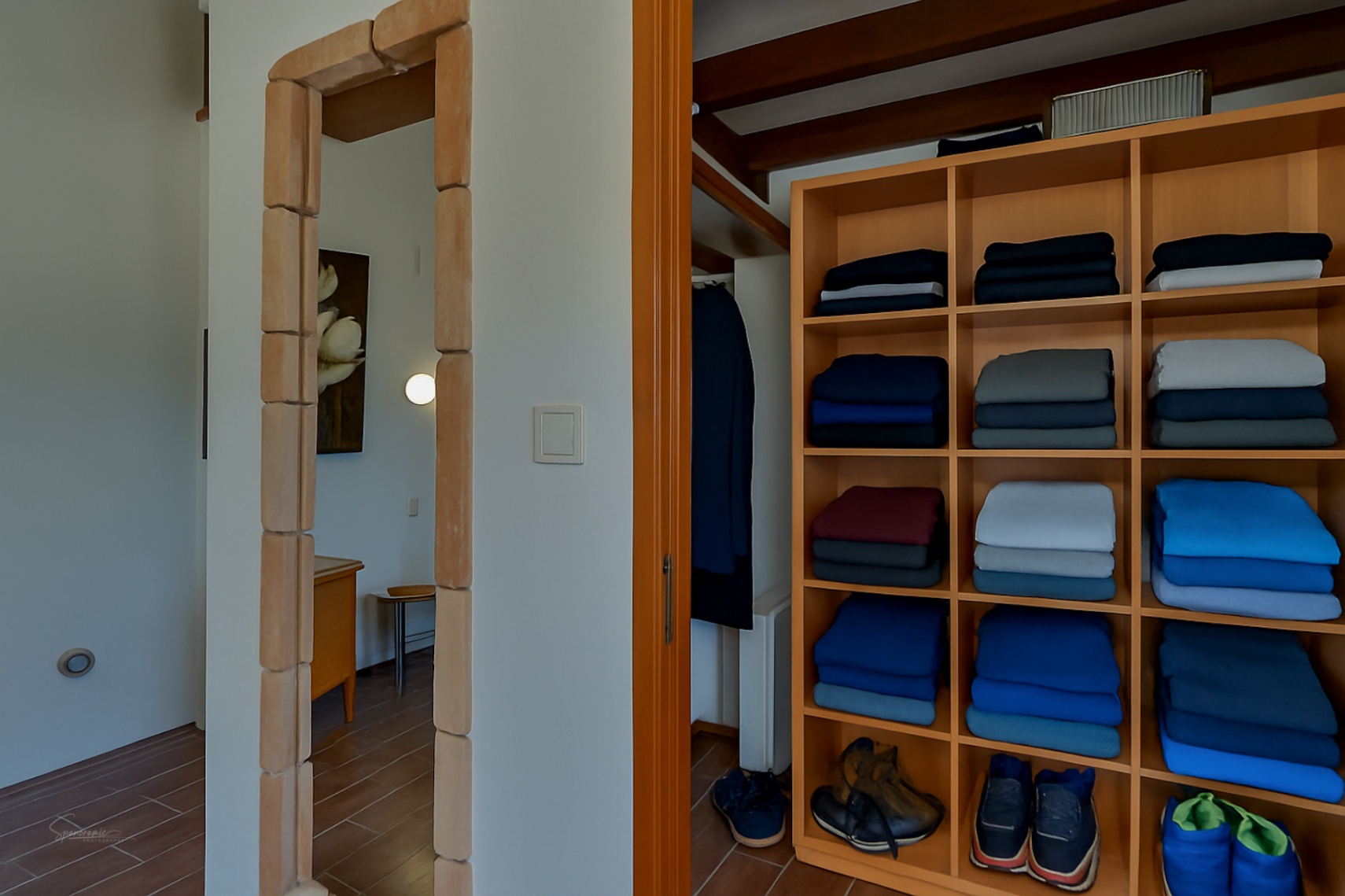 Detail van kleedkamer met lichte houten planken en een deuropening met stenen frame in Teulada.