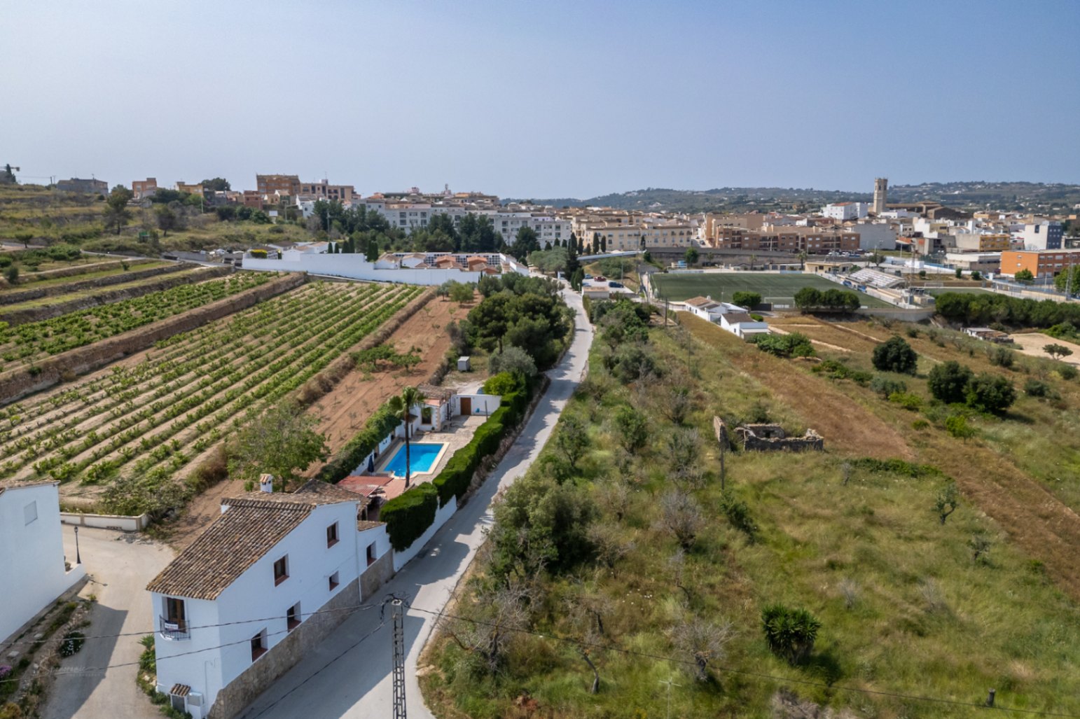 Luchtfoto van een landhuis met zwembad in Teulada, omgeven door wijngaarden en mediterrane vegetatie.
