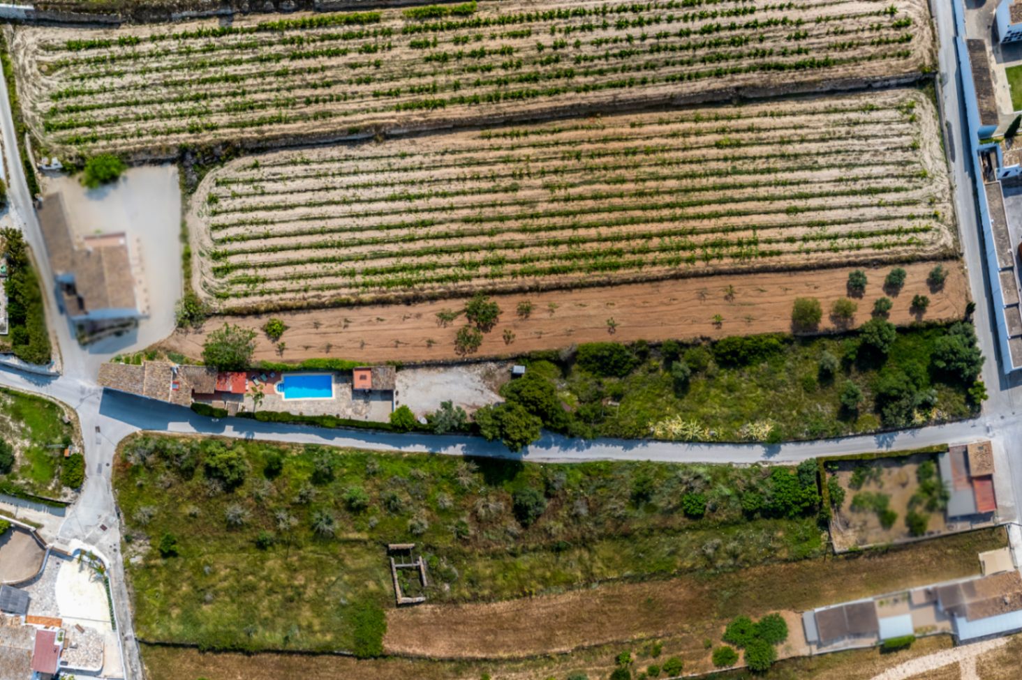 Luchtfoto van een rustieke finca met zwembad in Teulada, omgeven door landbouwgrond en mediterrane vegetatie.
