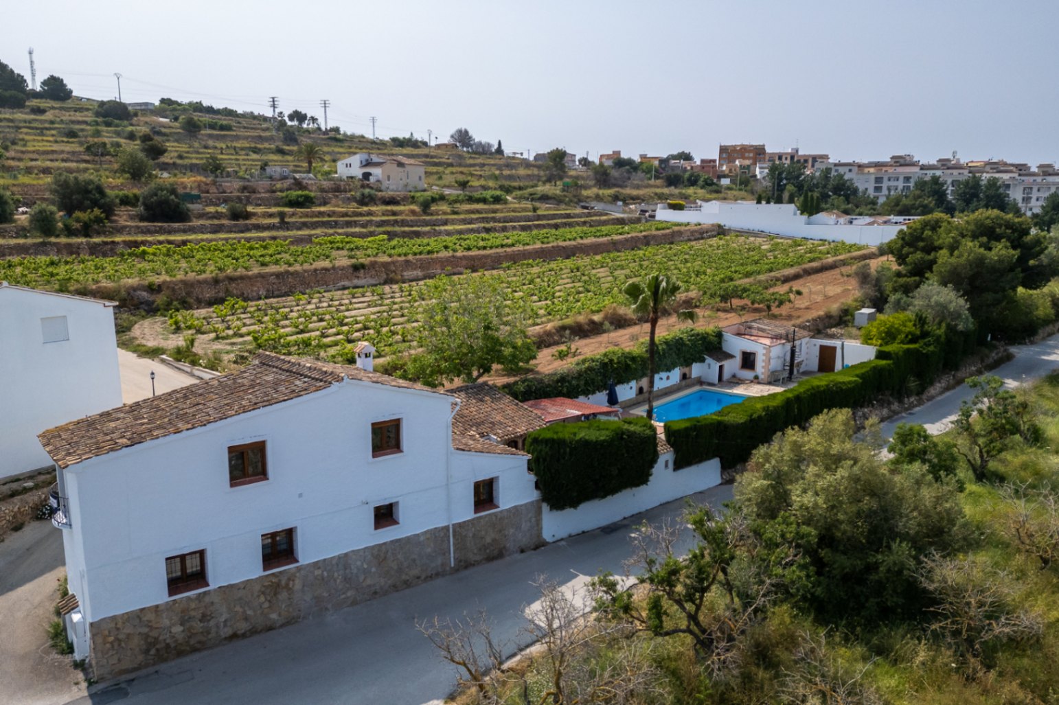 Luchtfoto van wit landhuis met zwembad, omgeven door wijngaarden in Teulada, Costa Blanca.