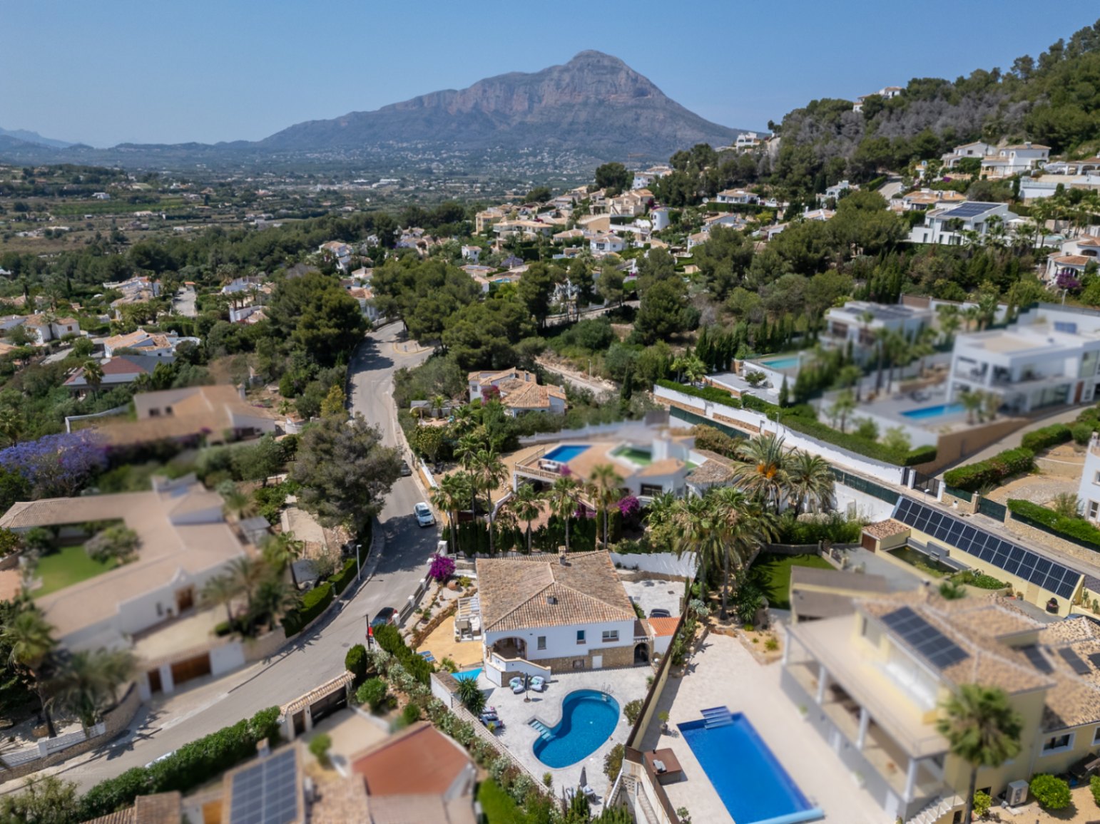 Luchtfoto van villa met privézwembad in Jávea. Residentiële omgeving met groen en uitzicht op de bergen.