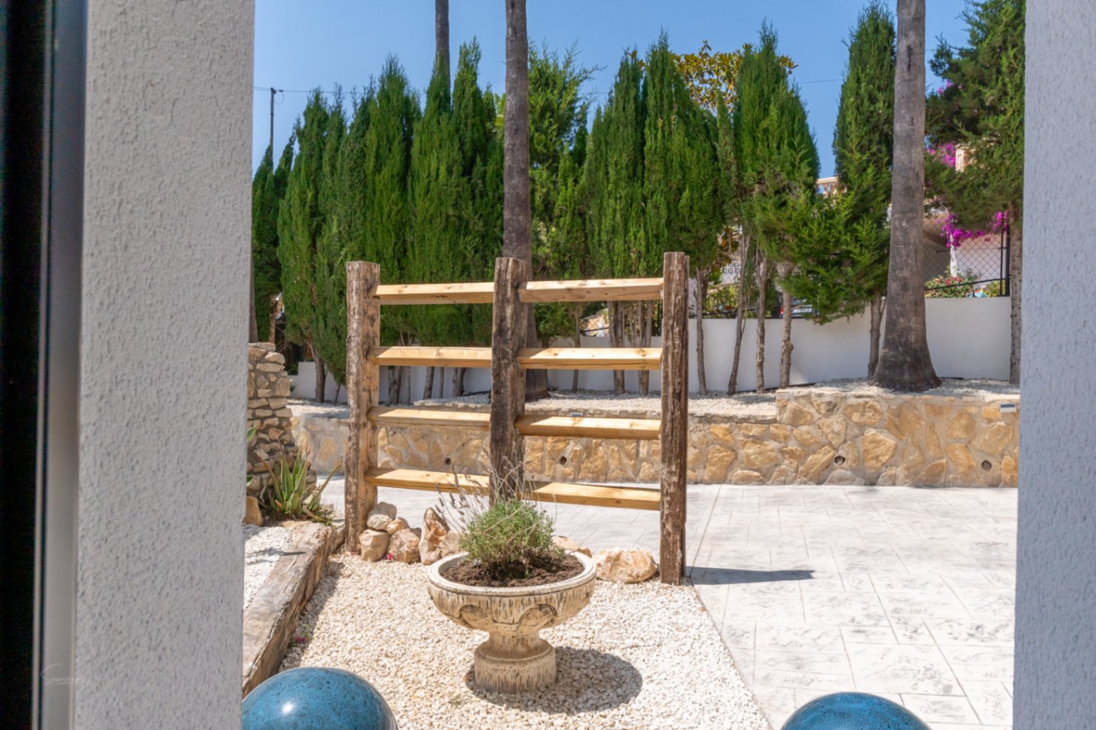 Tuindetail met rustieke houten stelling en sierlijke plantenbak in Jávea.