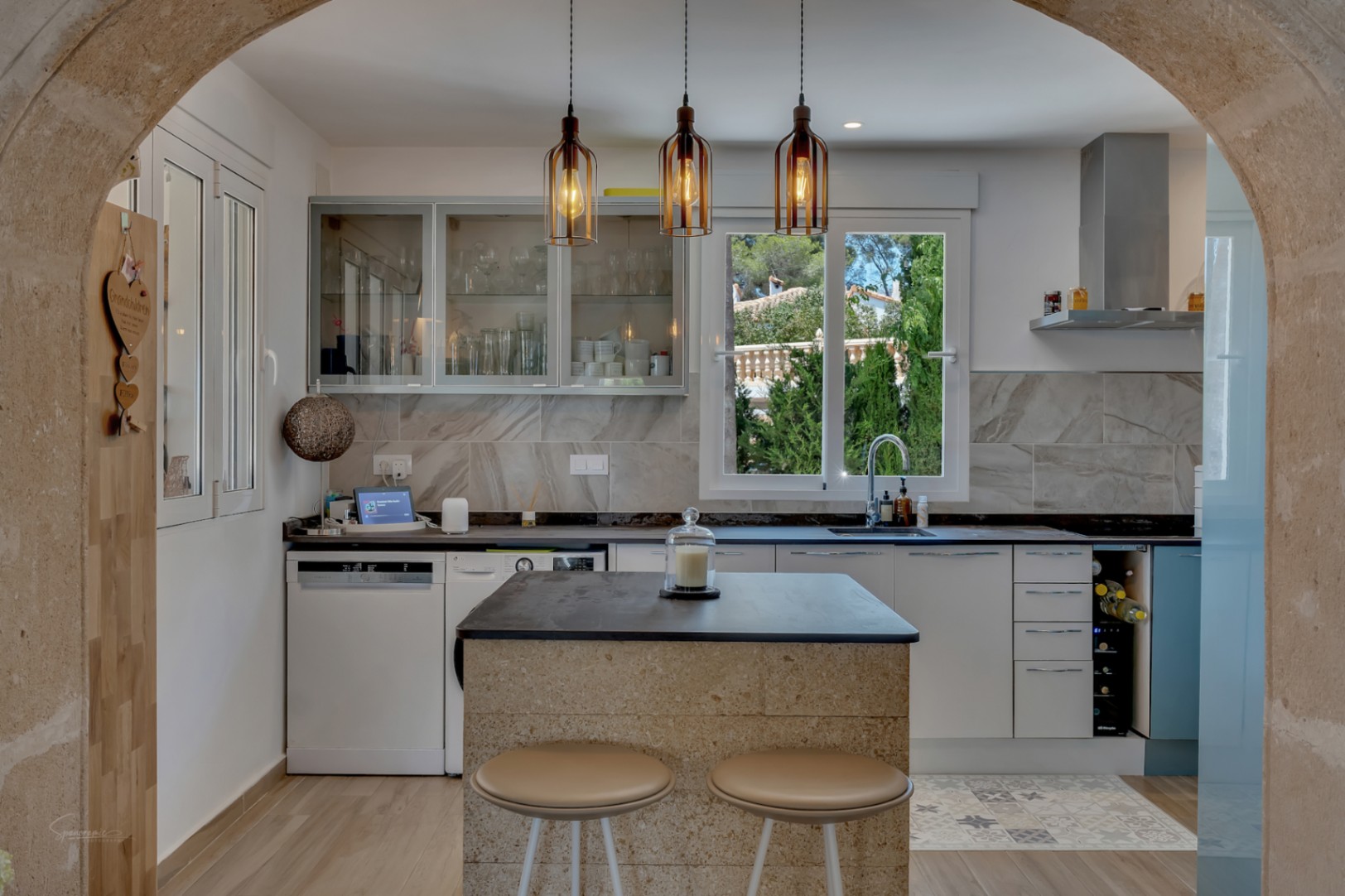Zicht op de moderne keuken met stenen eiland en design hanglampen.