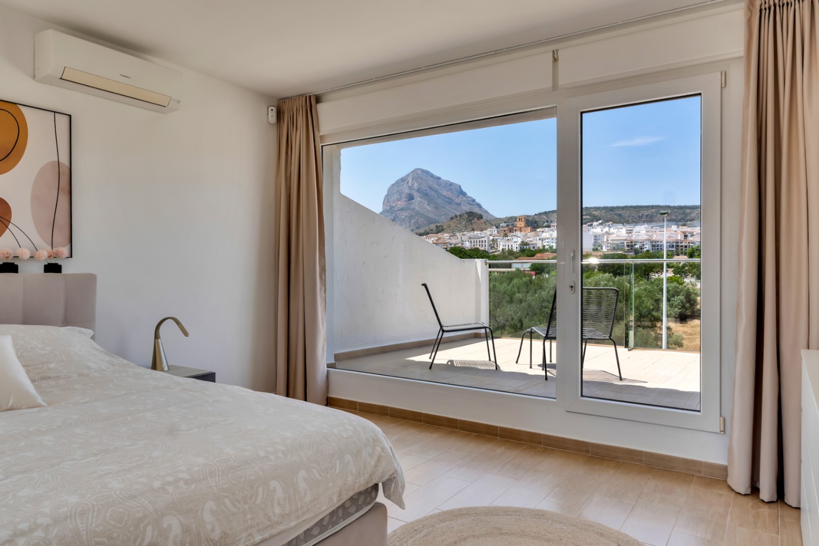 Hoofdslaapkamer met toegang tot een privéterras en panoramisch uitzicht op de Montgó. Voorzien van airconditioning, moderne afwerking en veel natuurlijk licht.