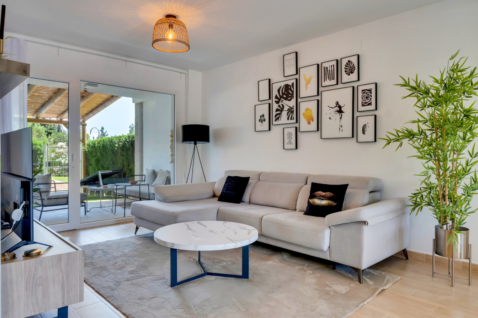 Lichte woonkamer met een moderne hoekbank, marmerlook salontafel en directe toegang tot het privéterras via grote glazen schuifdeuren.